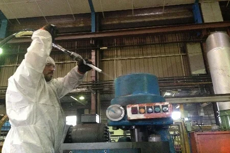 Formation nettoyage cryogénique professionnel: opérateur en combinaison purgeant une machine industrielle avec outil de nettoyage cryogénique.