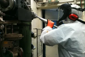 Homme travaillant avec un nettoyeur cryogénique sans eau sur une pièce métallique dans un atelier, émission de gaz froid dense. yage cryogénique sans eau chimique intégré.